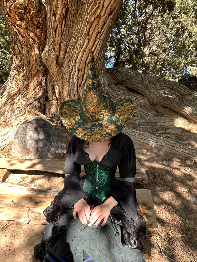 Person sitting on a rock with a patterned cushion, surrounded by trees and natural light.